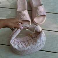 Světlá růžová woven kabelka z veganské kůže v letním stylu, focená vedle značkových růžových pantoflí.