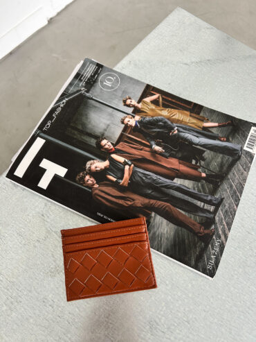 Hnědý cardholder z vegan kůže položený na módním magazínu, minimalistický unisex doplněk.